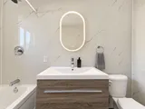 Bathroom vanity and illuminated oval mirror — Modern 3BR Spacious Home