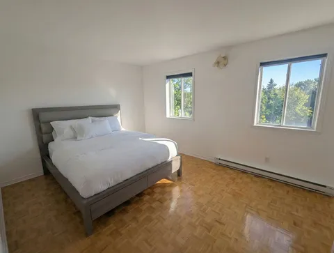 Bedroom with window and bedside tables — Spacious 2BR Holiday Home Near YUL