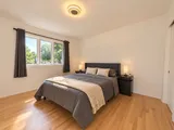 First queen bedroom with bedside tables and large window — Modern 3BR Spacious Home