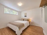 First queen bedroom with wood bed frame and warm bedside lighting — Cozy 2-Bedroom Retreat