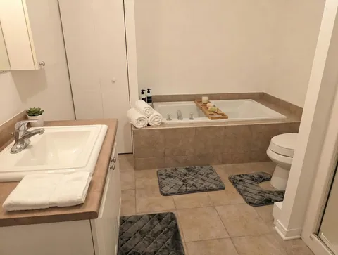 Bathroom with bathtub and vanity — Spacious 2BR Holiday Home Near YUL