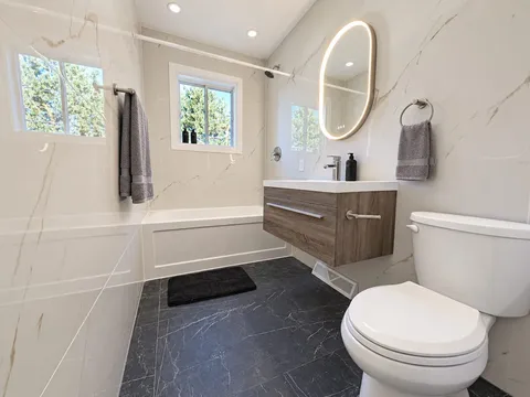 Bathroom with bathtub, vanity and illuminated mirror — Modern 3BR Spacious Home