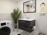 Bathroom with sink and stacked laundry appliances — Stylish Modern 1BR with EV Charger