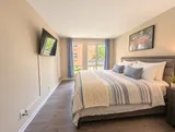 Queen bedroom with TV and courtyard-facing windows — Bright 2BR Retreat
