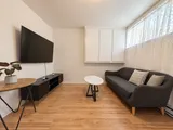 Living room seating opposite the wall-mounted TV — Cozy 2-Bedroom Retreat