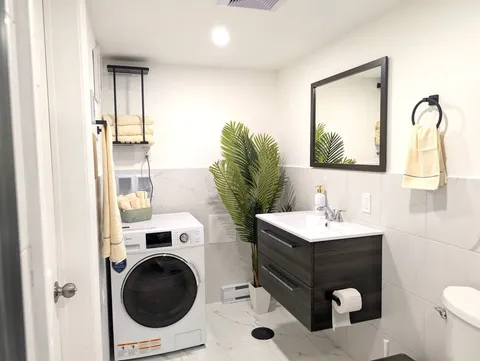 Bathroom with sink and stacked laundry appliances — Stylish Modern 1BR with EV Charger