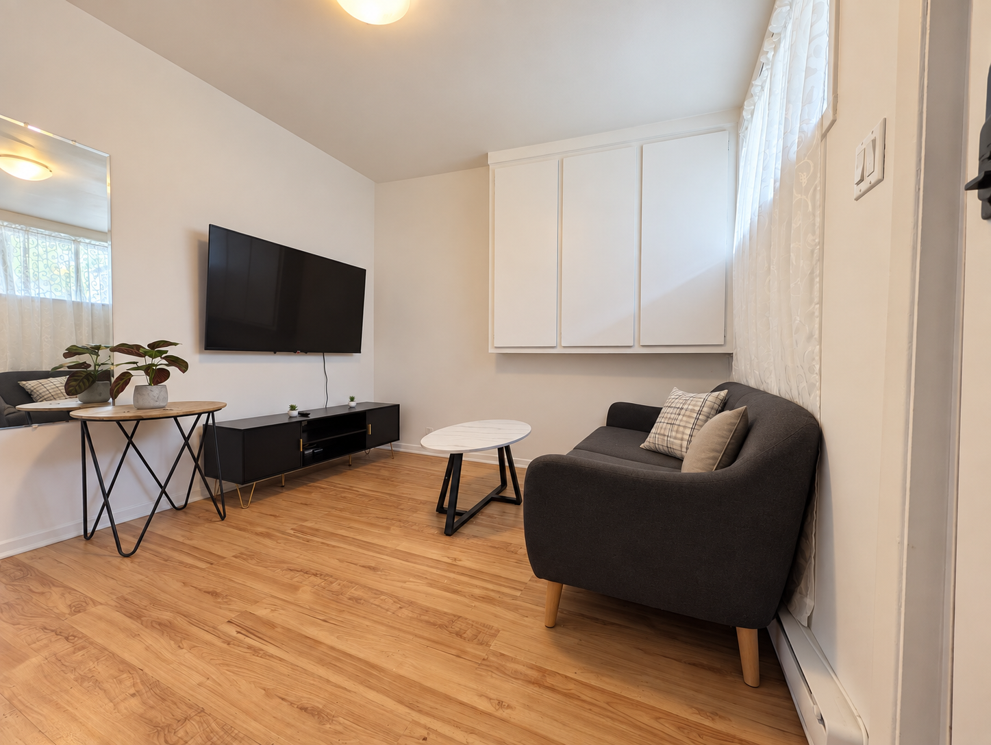 Living room with sofa, wall-mounted TV and coffee table — Cozy 2-Bedroom Retreat in Longueuil